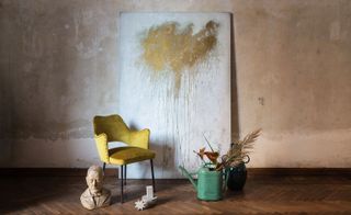 Yellow chair with painted canvas behind and decorations on floor