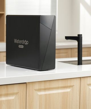 Black Waterdrop X16 on white marble kitchen counter. It is a rectangular upright tower with white company branding on the side