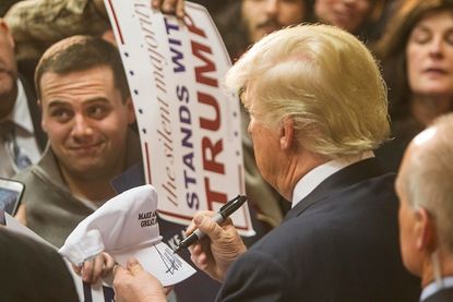 Donald Trump signs a fan's hat.