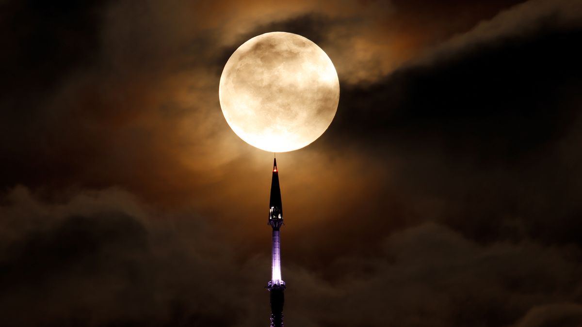 Full Super Flower Moon rises behind the antenna on top of One World Trade Center in New York City .