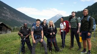 Daliso Chaponda, Harry Clark, Stef Reid, Helen Lederer, Nelufar Hedayat, Jay McGuiness and Jeff Brazier stands in the Alps with backpacks and walking sticks in Pilgrimage: The Road Through the Alps