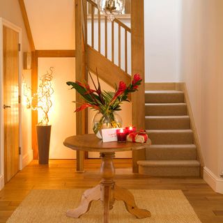 hallway with staircase wooden flooring wooden round table and flower pot