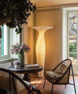 A sculptural, glowing light fixture in the corner of a living room, next to a small wooden table and two chairs