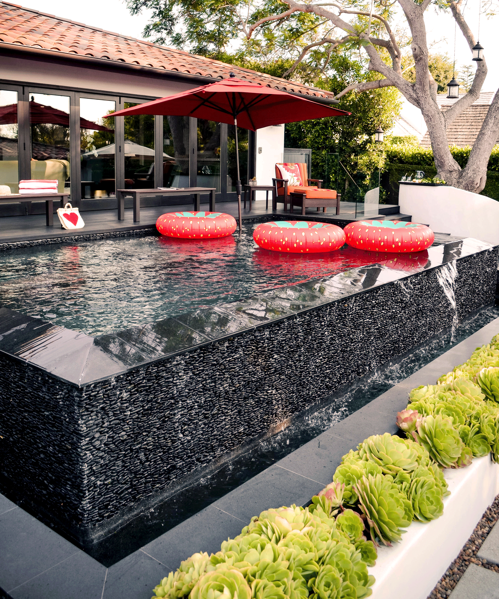 black plunge pool with red inflatables and red umbrella