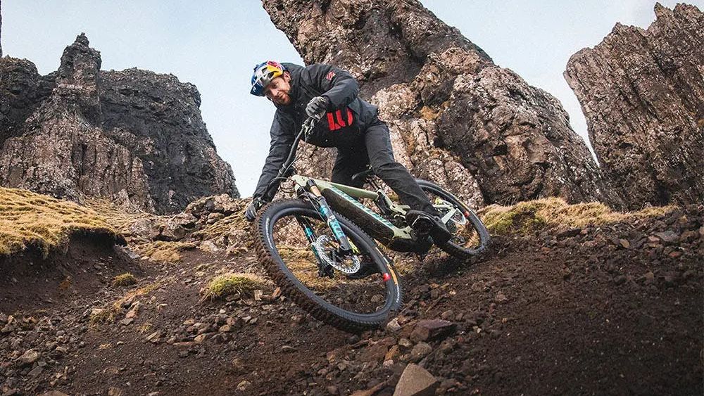 Danny MacSkill riding the Santa Cruz Heckler e-MTB under some rocky outcrops