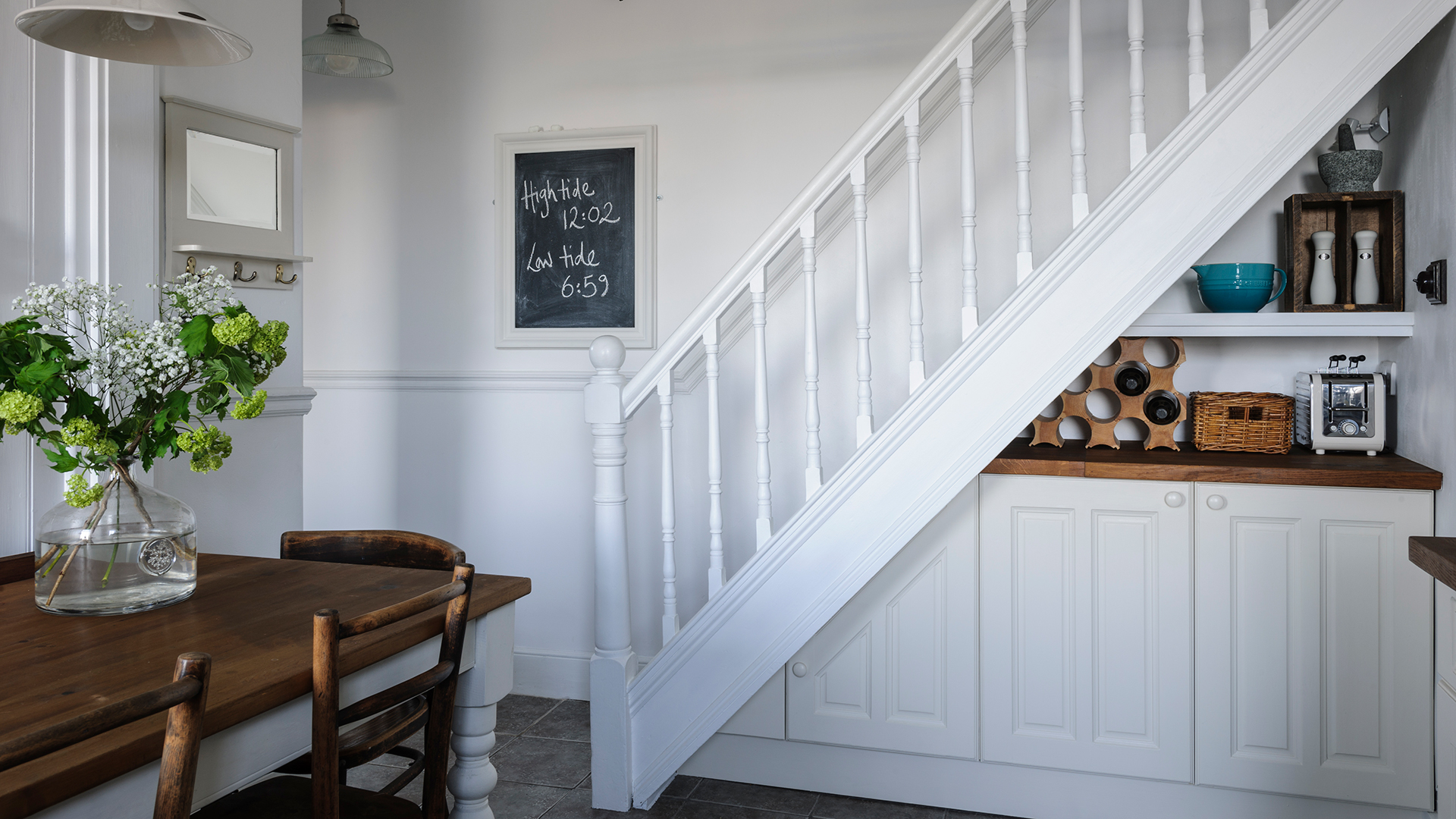 White kitchen dining area with cabinets built-in under the stairs to maximise space