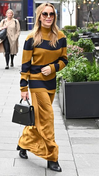 Amanda Holden wearing satin maxi skirt, striped knit jumper and black heeled boots