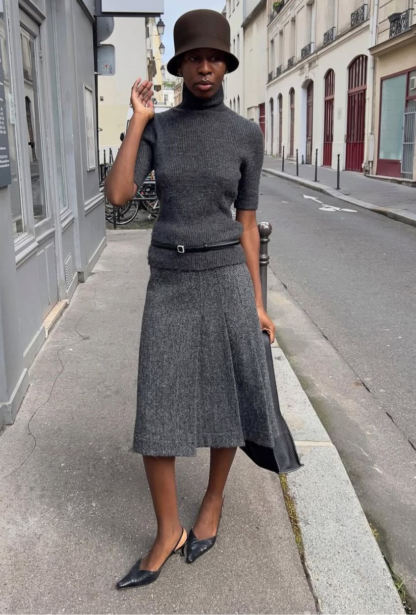 @sylviemus_ wears a grey wool skirt with a short-sleeve knit, black mules and brown bucket hat