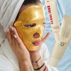 woman in a gold sheet mask and robe with two bottles of skincare