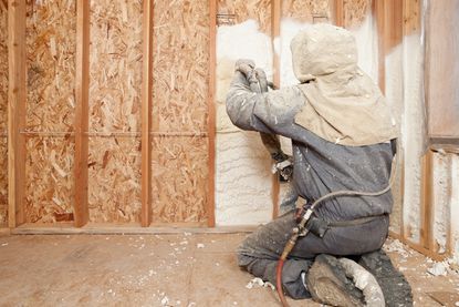 Worker Spraying Expandable Foam Insulation between Wall Studs