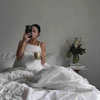 Woman wearing a sheet mask and taking a selfie on an iPhone