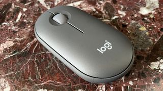 The Logitech Pebble Mouse 2 M350S mouse from behind on a marble worktop.