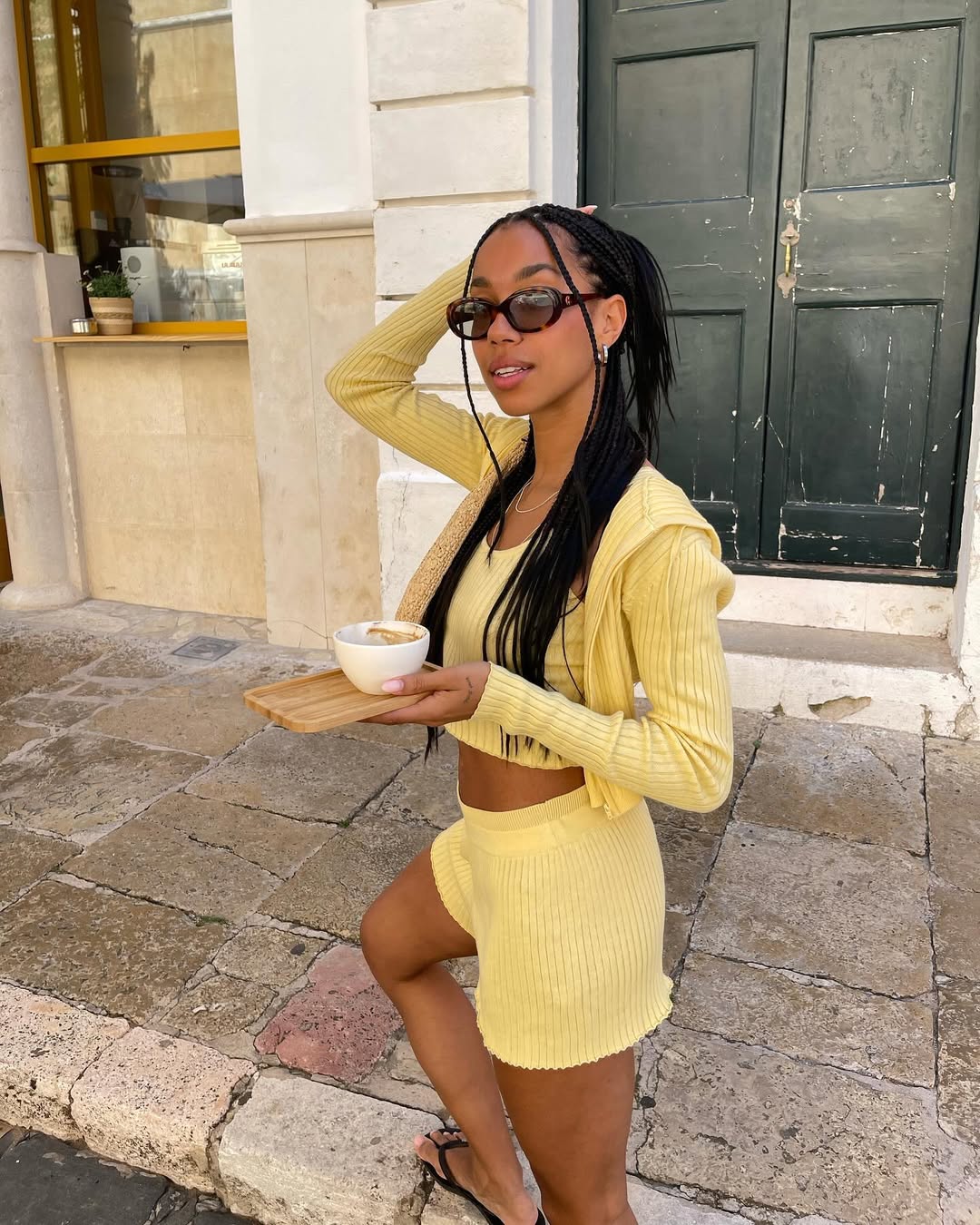 Amaka in a yellow cardigan and matching shorts