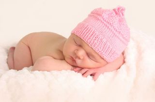 Newborn baby with a pink hat on