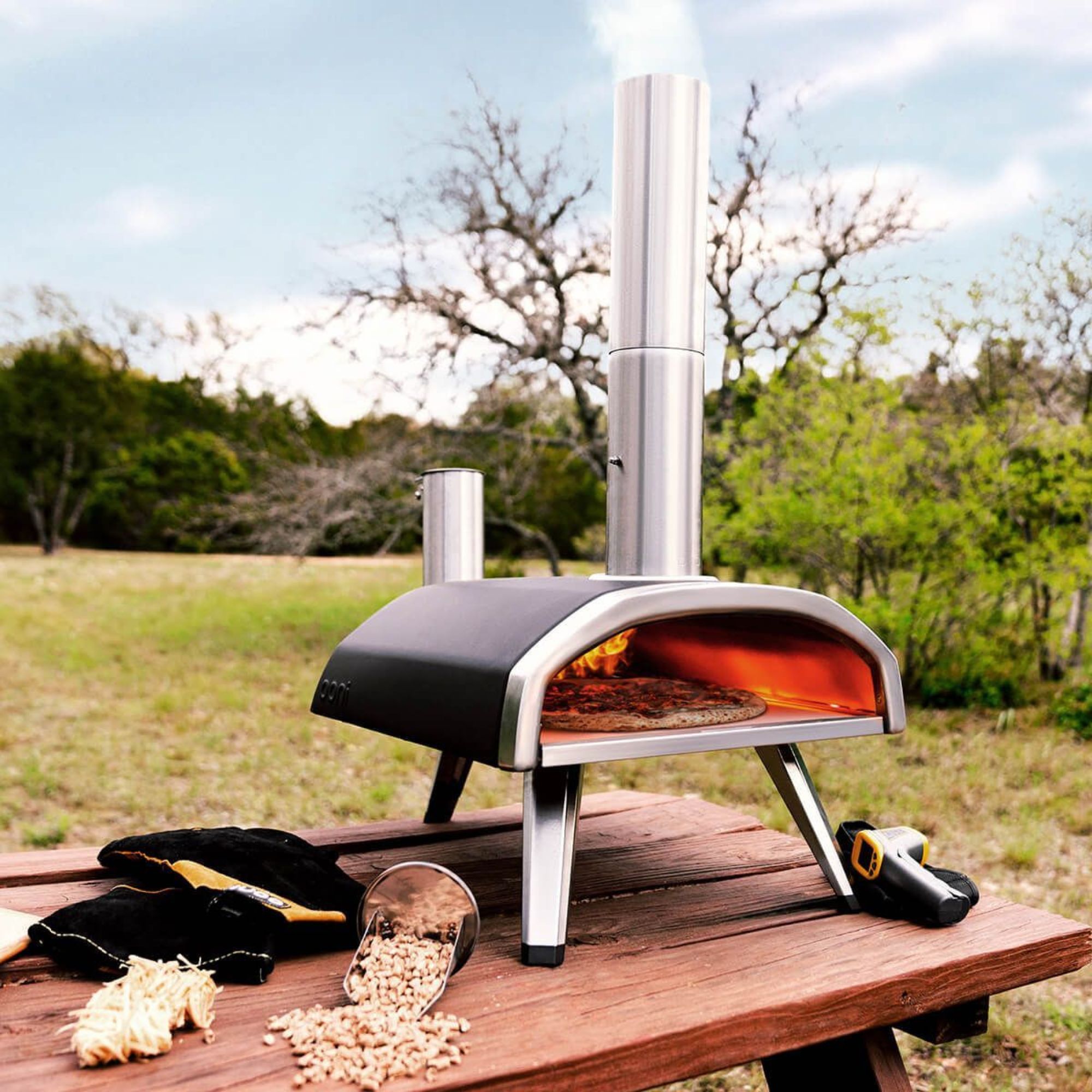 Ooni Fyra 12 on a wooden table against a grass background. 