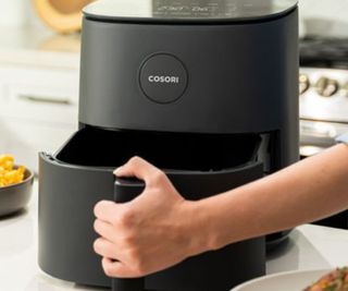A hand opening the drawer of the Cosori Pro LE Air Fryer.