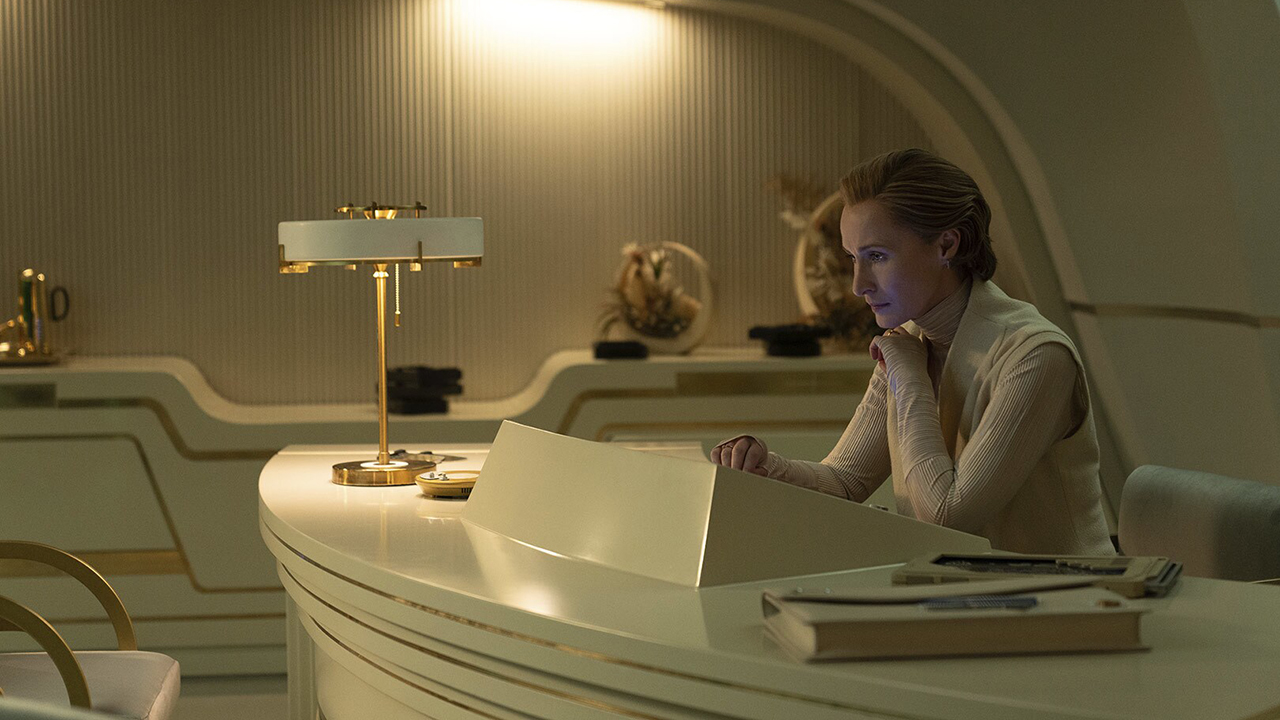 Still from the Star Wars TV show Andor. Mon Mothma examining sensitive information. She is sitting at a sleek white desk with beautiful gold accents.