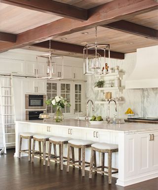 Kitchen with island with double sinks, double pendants hanging overhead, and five bar stools