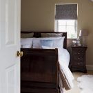 master bedroom with wooden sleigh bed and furry white rug on floor