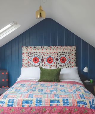 attic bedroom with blue walls and patterned headboard and bedspread