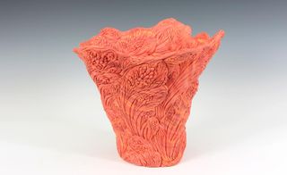 An intricately carved orange ceramic vessel