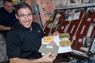 NASA astronaut Michael Hopkins, Expedition 38 flight engineer, holds a Thanksgiving meal in the Unity node of the International Space Station. Photo dated Nov. 28, 2013.