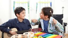 Two young boys, one with cerebral palsy, playing musical instruments. 