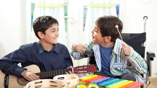 Two young boys, one with cerebral palsy, playing musical instruments.