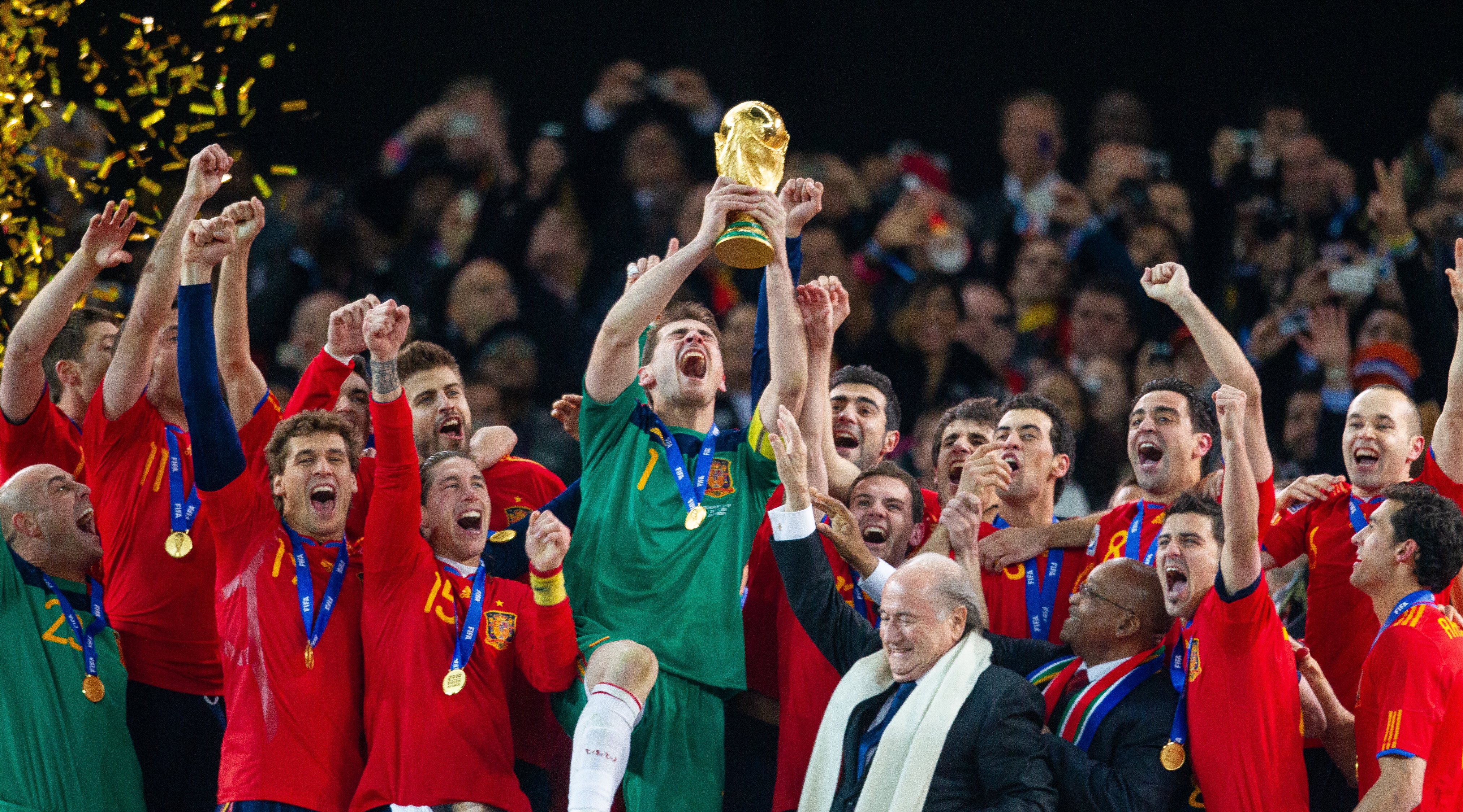 Spain goalkeeper and captain lifts the World Cup trophy after being handed it by Sepp Blatter, FIFA President and Jacob Zuma President of South Africa and surrounded by the Spanish team after victory in the World Cup Final match between Spain (1) and Netherlands (0) at the FNB Stadium on July 11, 2010 in Johannesburg, South Africa