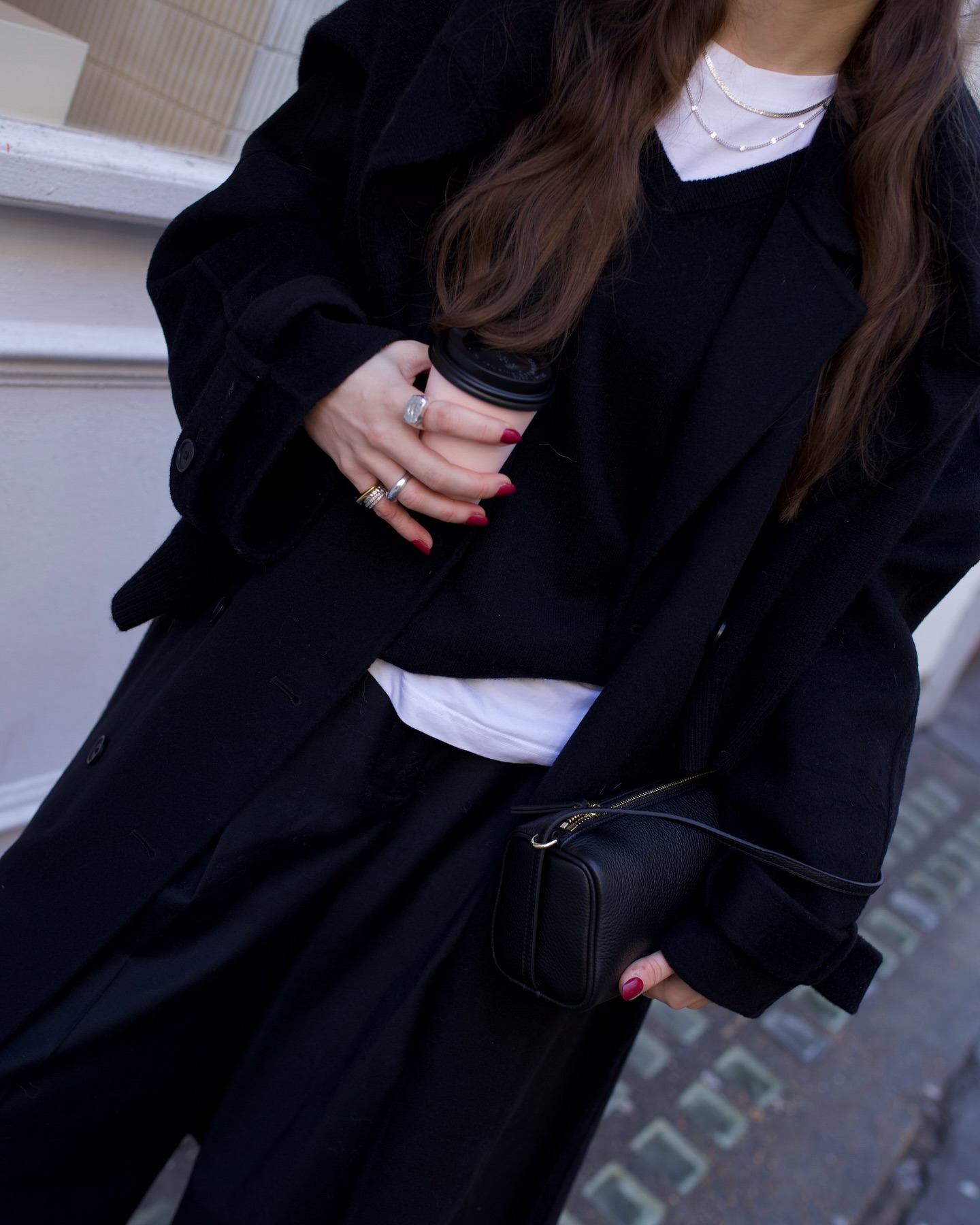 A woman holding a takeaway coffee cup with a bold red manicure