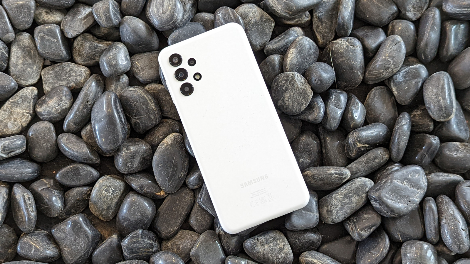 The back of the Samsung Galaxy A13 on a surface of pebbles