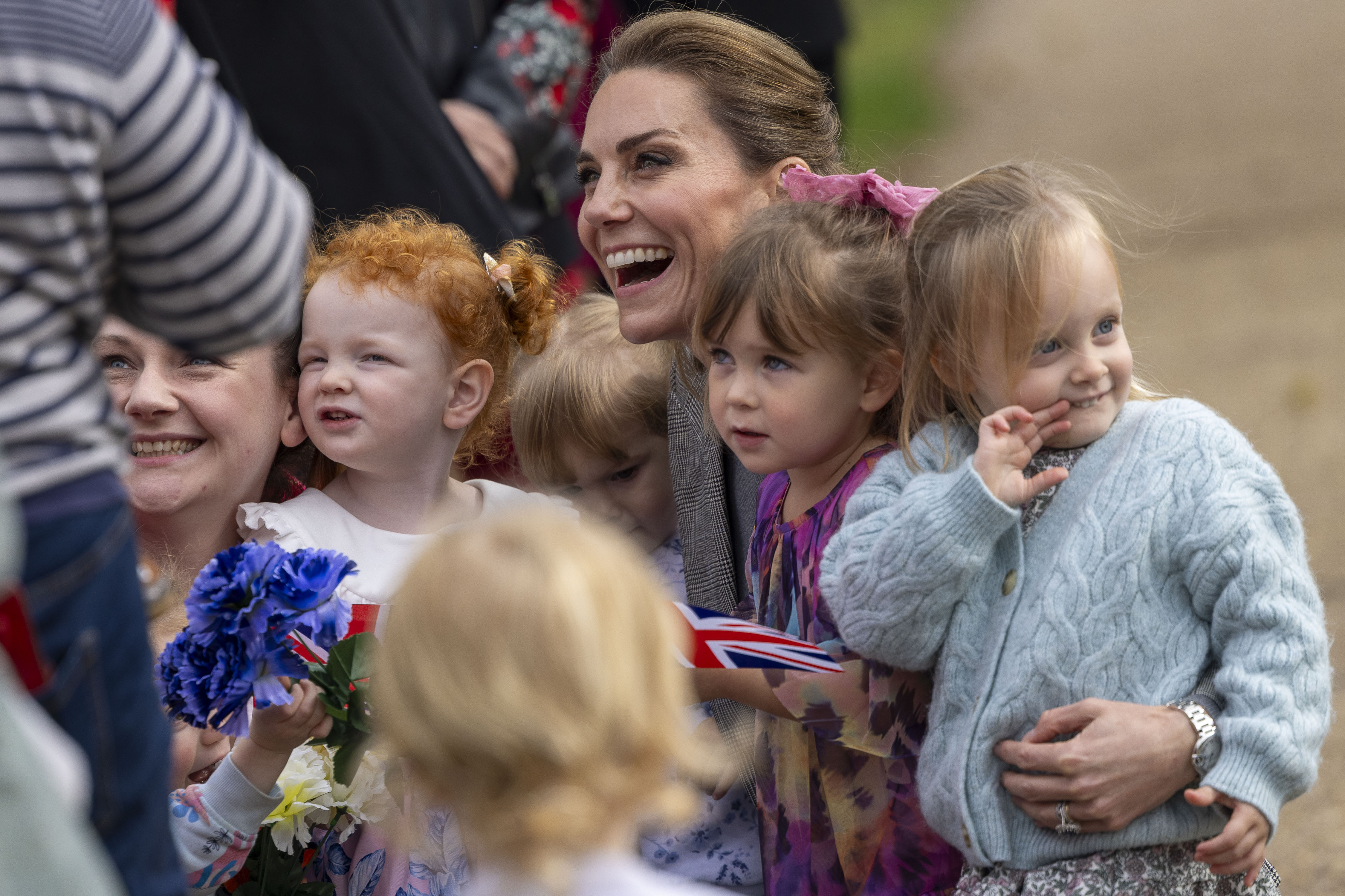 Kate Middleton kneeling down and posing with four little girls for a photo