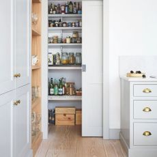 Kitchen area with grey cupboards and a pantry area filled with food