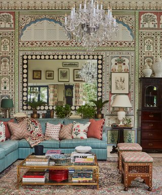 maximalist living area with lots of pattern on rugs, sofa, cushions, walls with chandelier and mirror and coffee table