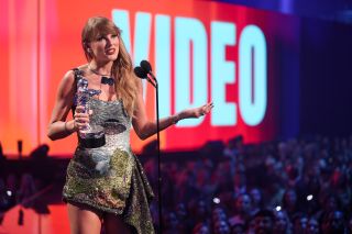 Taylor Swift accepts the Video of the Year award for "Fortnight" onstage at the 2024 MTV Video Music Awards in a mini dress that has a UFO on it.