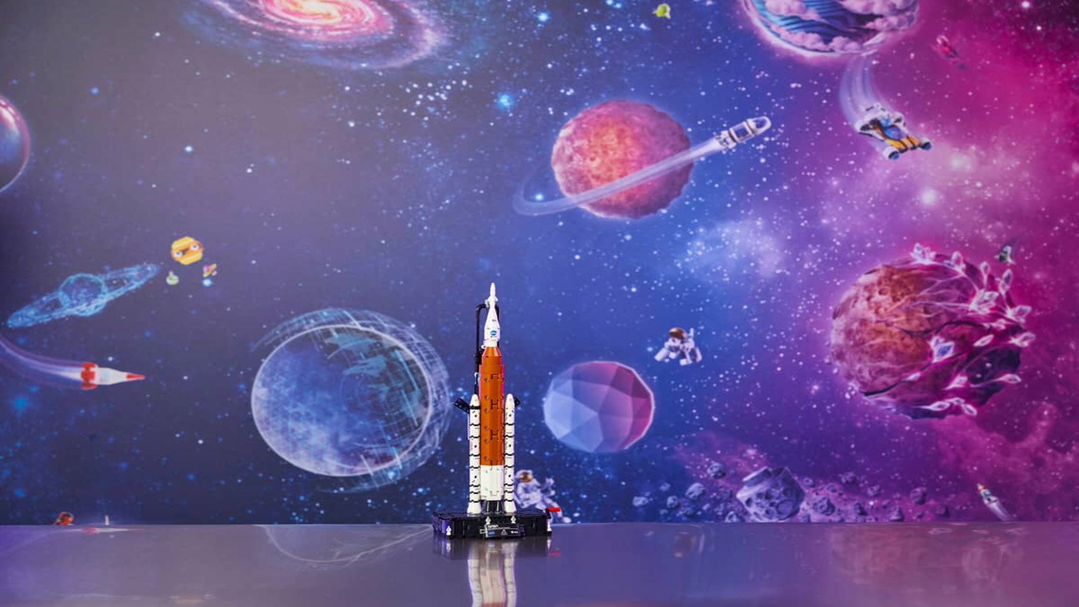 A white and orange rocket is displayed upright in front of a purple and pink planet background.