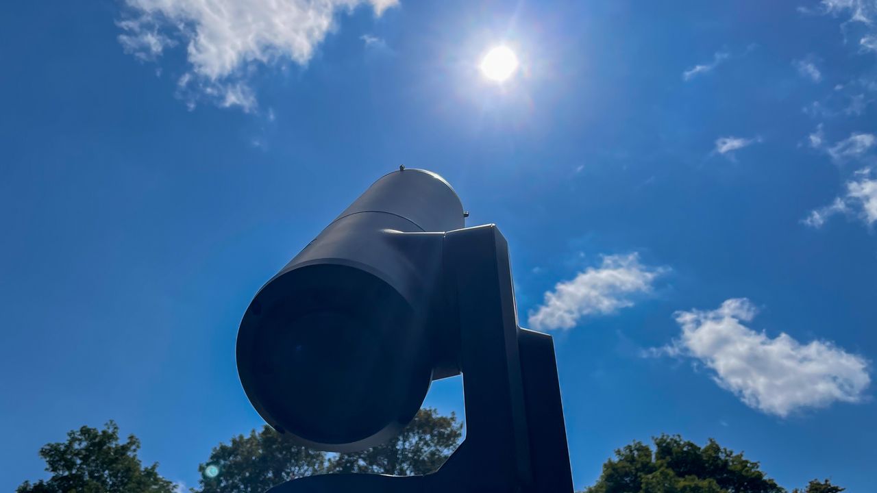 A Unistellar eVscope 2 pointing at the sun in the blue sky.