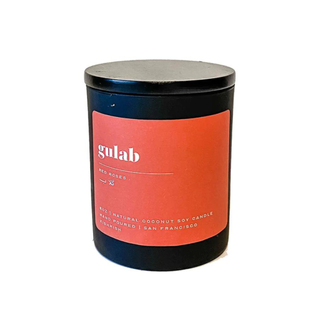 A black candle with a red-orange label and gulab rose scent