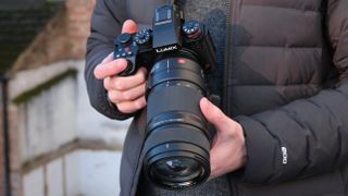 Panasonic Lumix S1R II camera with 70-200mm lens attached held in a person's hands