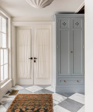 light and bright entryway with light blue storage cabinets and a classic black and white marble checkerboard floor