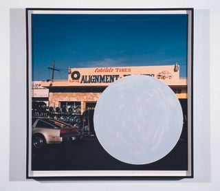 Framed picture of an automobile tyre store, with a big white cycle on the bottom right of the image