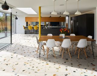 terrazzo flooring in a large kitchen with bar stools and a dining area