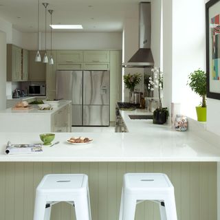 kitchen with white wall and marble countertop and sage green cabinets