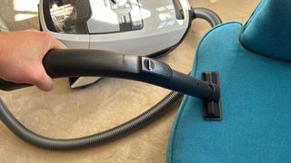 Miele Blizzard CX1 canister vacuum cleaning a sofa