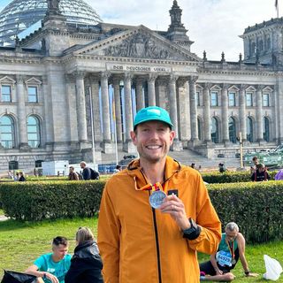 Nick Harris-Fry poses with his Berlin Marathon finishers medal in front of the Reichstag building