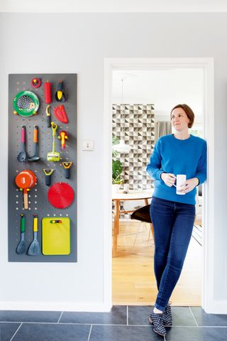 Jessica Preston stands in the doorway of her kitchen next to a pegboard used to store utensils