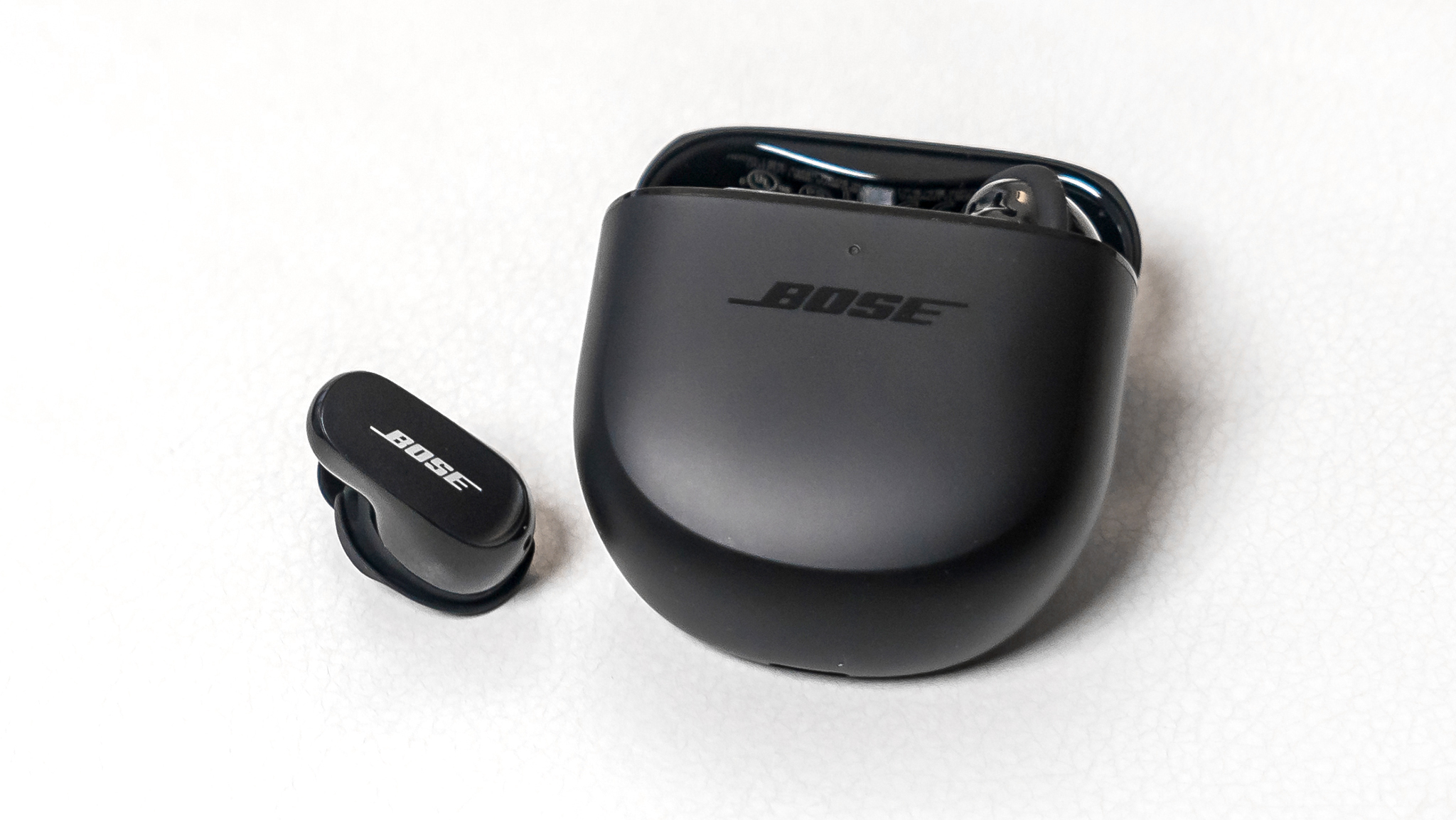 Bose QuietComfort Earbuds II solto ao lado do estojo.