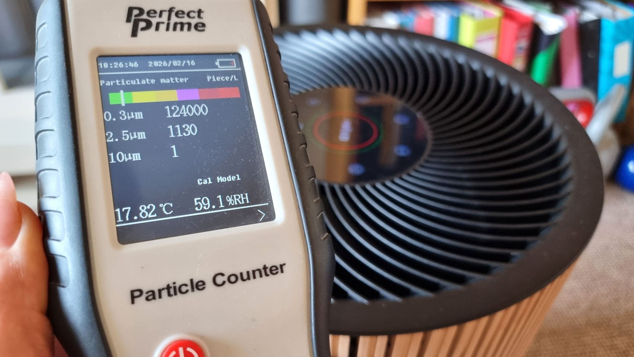 A close-up picture of our reviewer testing the IQAir Atem Earth air purifier using the Perfect Prime air particle monitor