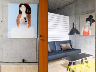 Left: orange door opens to a room with a piece of painted artwork on the wall. Right: seating area with low-hanging light and more artwork