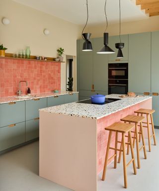 A pink and blue IKEA kitchen with custom fronts from Plykea, terrazzo countertops, and a pink tile backsplash